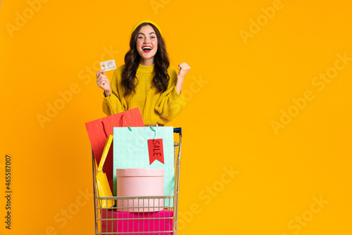 White woman posing with credit card and shopping cart