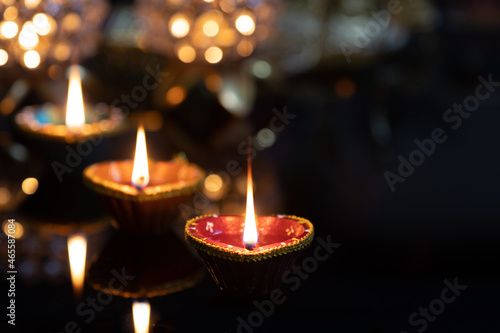 Eco Friendly Clay Diya Deep Dia Glowing lamps on a reflective base Hindu festival Laxmi pooja (Diwali),with glittering background bokeh