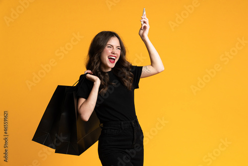 White excited woman posing with shopping bags and cellphone