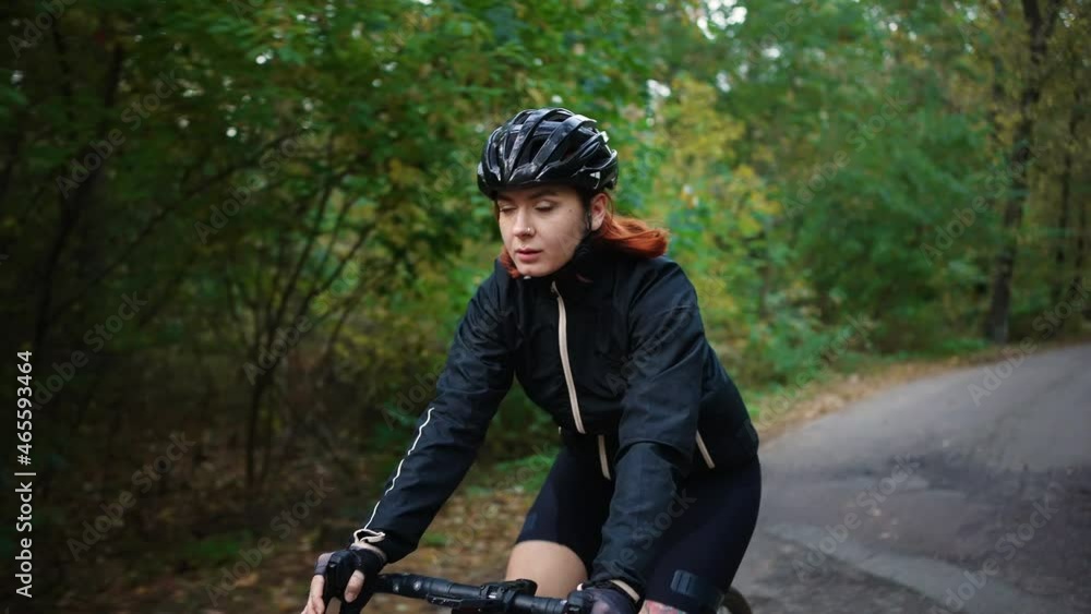 Biking adventures. Young active woman riding road bicycle in forest, twisting pedals on bike along on woods road Biking adventures. Young active woman riding road bicycle in forest, twisting pedals on bike along on woods road