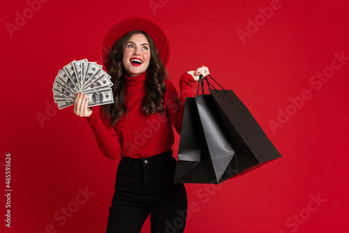 White woman laughing while posing with shopping bags and dollars © Drobot Dean