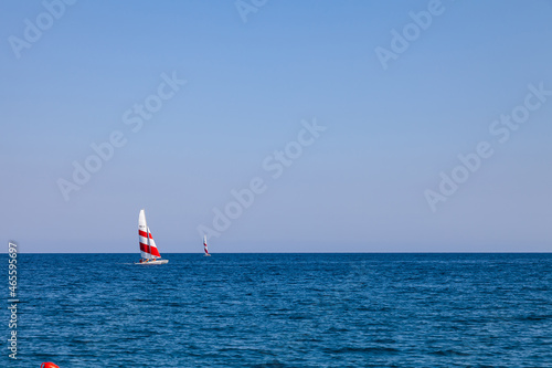 Regatta sailing ship yachts with red and white sails at opened sea. Aerial view of sailboat in windy condition