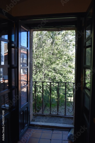 Wooden window and an old metal balcony overlooking a garden