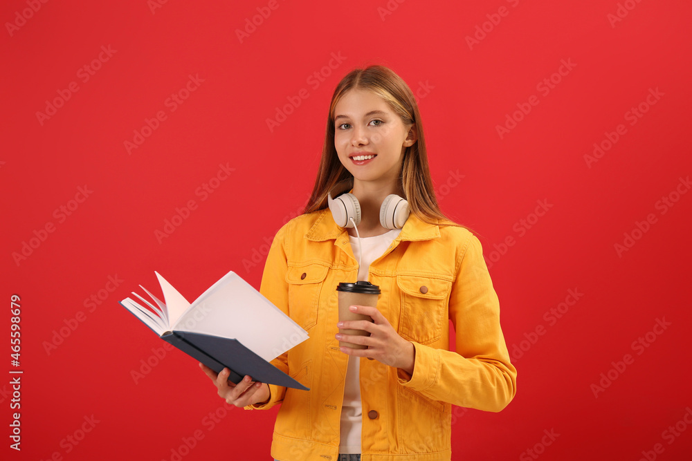 Teenage student with book, cup of coffee and headphones on red background Teenage student with book, cup of coffee and headphones on red background