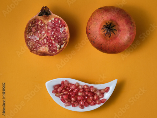 Some pomegranate fruits opened against a yellow bakcground. Pomegranate minimalist kitchen decoration background © Julian