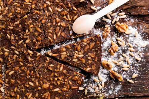 close up of traditional castagnaccio cake slice, a classic italian gluten free autumn cake on wooden table made with chestnuts flour, pine nuts, rosemary and olive oil. italian bakery healthy food. photo