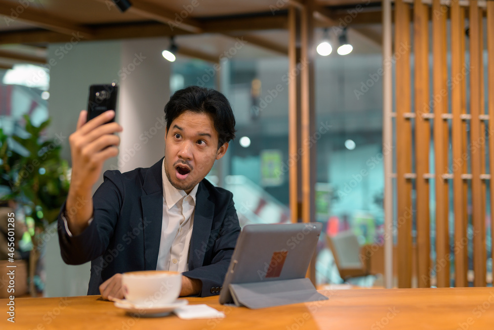 Portrait of Asian businessman in coffee shop using digital tablet computer and mobile phone Portrait of Asian businessman in coffee shop using digital tablet computer and mobile phone