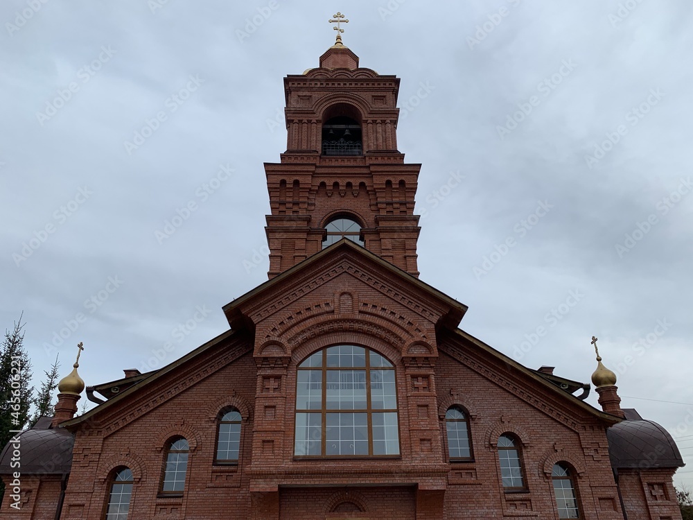 Orthodox church made of red bricks with golden baths and a cross