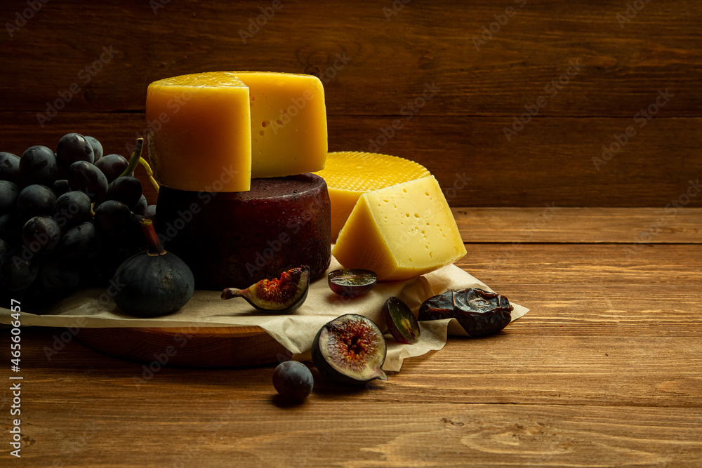 composition of different types of sliced cheese: hard, mature, cheese with mold. Cheese slicing with fruit - grapes and figs. concept is cheese handicraft production, restaurant.