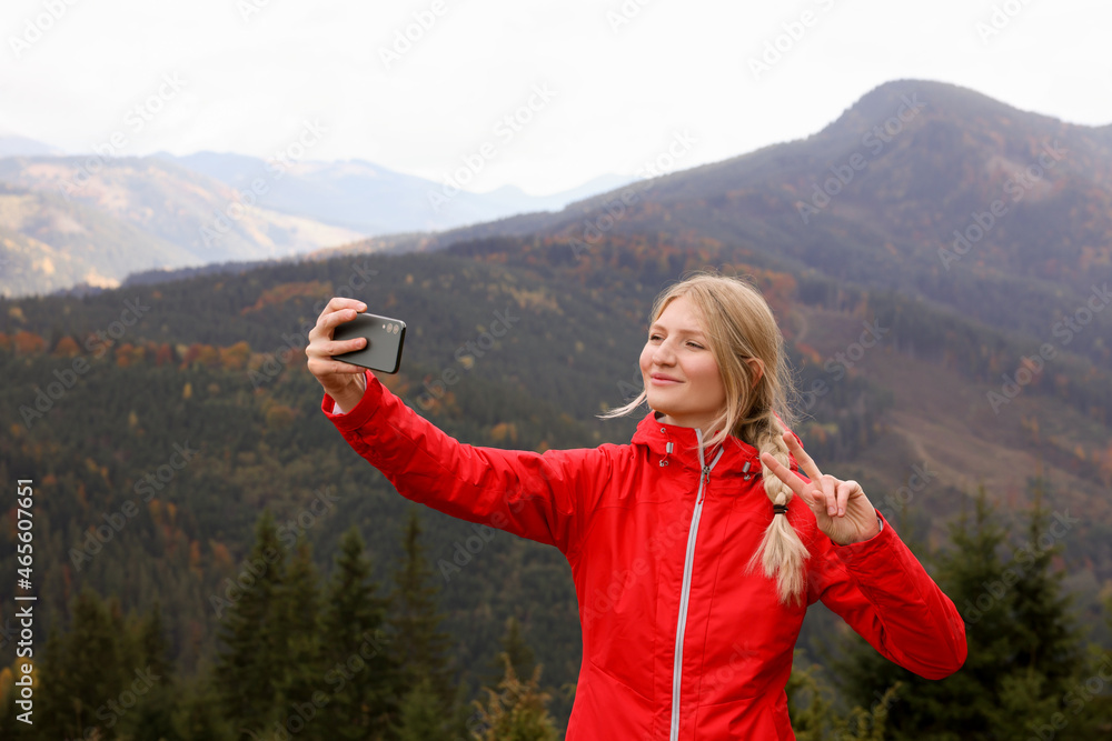 Happy young woman taking selfie with phone in mountains Happy young woman taking selfie with phone in mountains