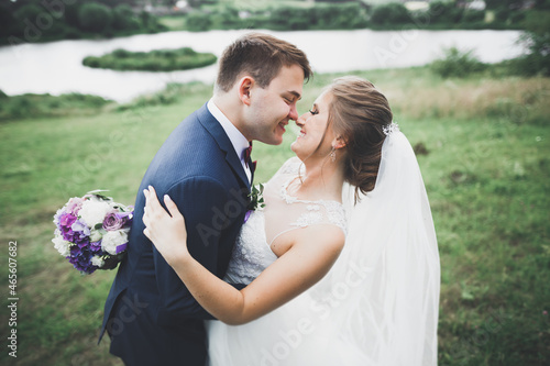 Romantic, fairytale, happy newlywed couple hugging and kissing in a park, trees in background