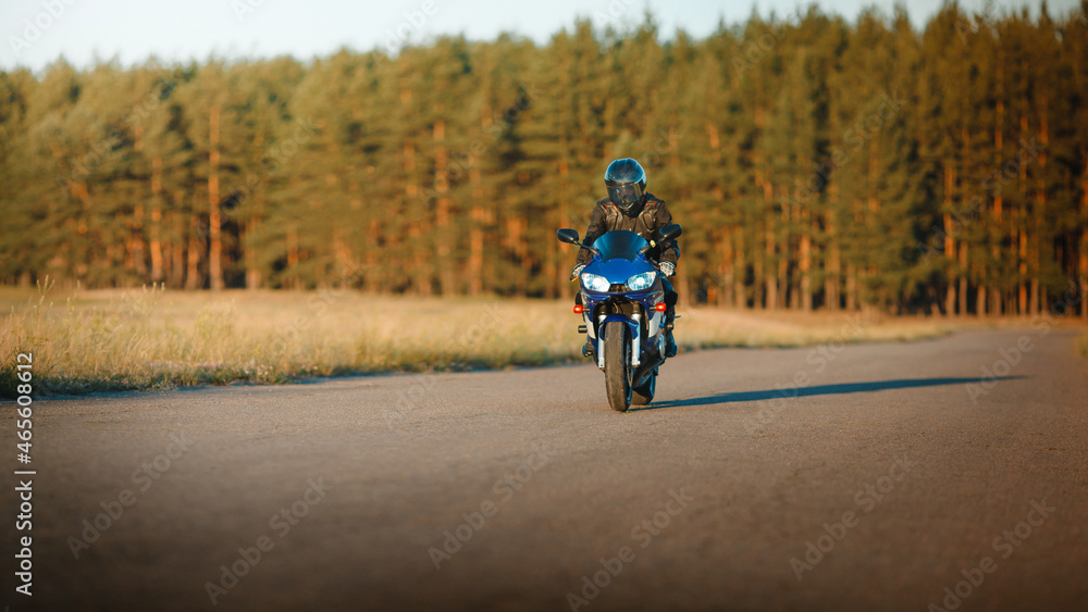 Biker in a protective suit with a helmet. Motorcyclist in a helmet and leather jacket rushes along the road on a sports motorcycle