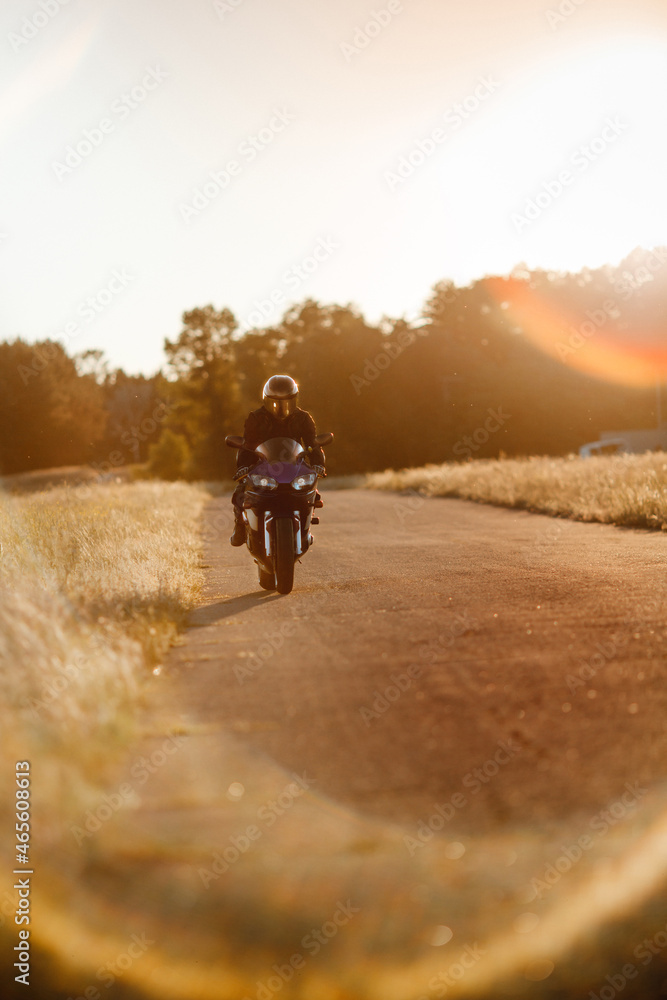 Biker in a protective suit with a helmet. Motorcyclist in a helmet and leather jacket rushes along the road on a sports motorcycle Biker in a protective suit with a helmet. Motorcyclist in a helmet and leather jacket rushes along the road on a sports motorcycle
