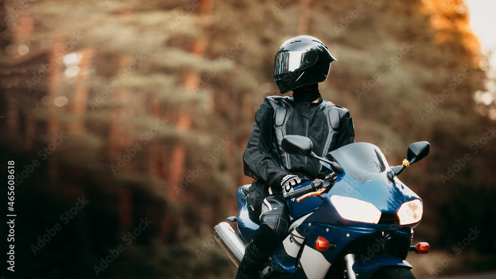 Biker in a protective suit with a helmet. Motorcyclist in helmet and leather jacket on the road on a sports motorcycle Biker in a protective suit with a helmet. Motorcyclist in helmet and leather jacket on the road on a sports motorcycle
