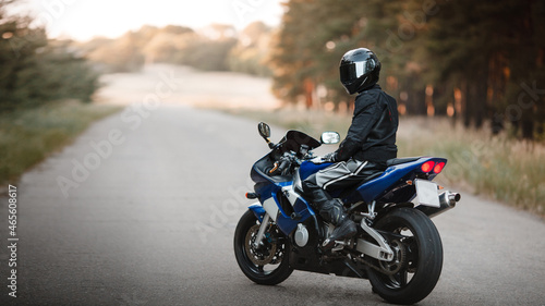 Biker in a protective suit with a helmet. Motorcyclist in helmet and leather jacket on the road on a sports motorcycle