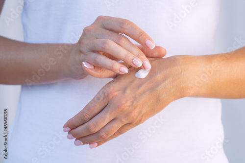 Woman applying moisturizer on her dry hands. Hand cream. Skin protection. Hand care or skin care concept