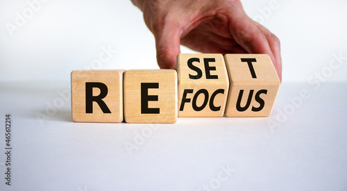 Refocus and reset symbol. Businessman turns cubes and changes the word 'refocus' to 'reset'. Beautiful white table, white background. Business refocus and reset concept. Copy space. photo
