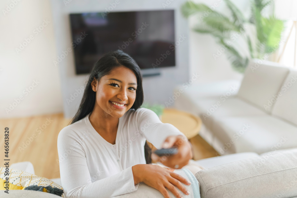 black woman watching television at home sit on sofa