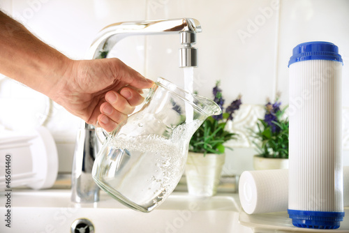 Hand filling jug from a tap with filtered osmosis water photo