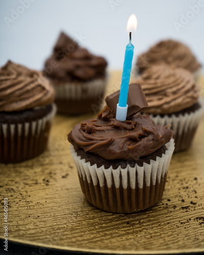 Chocolate cupcake with a golden plate with crumbs and a candle