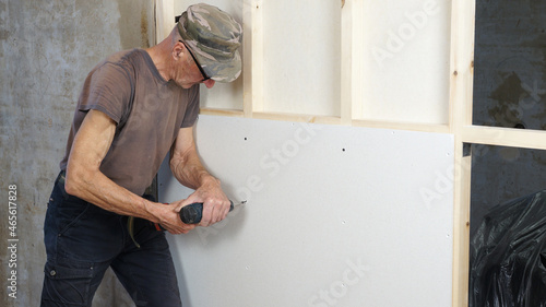 A man installs a gypsum gypsum panel