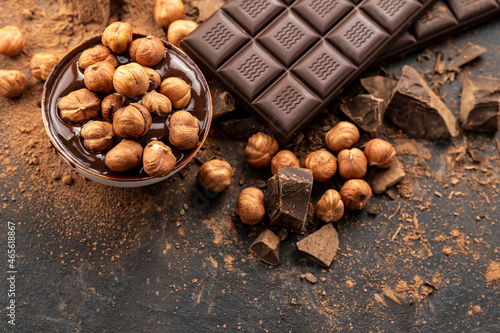 chocolate bar with hazelnuts, handmade sweets. Composition of bars dark chocolates hazelnuts on a black background, top view. Pastry craft on the table for chocolate background