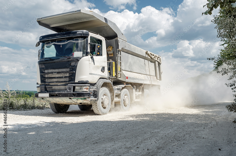 Industrial dump truck, transportation of stones, rides on a dusty road.Close-up. Career work