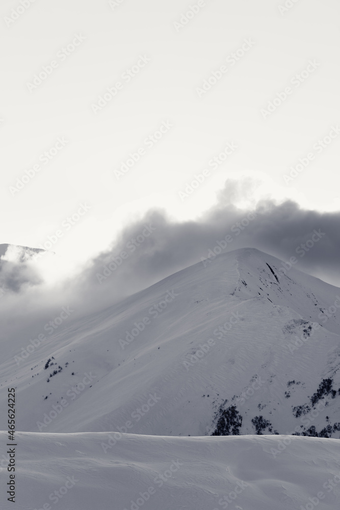 Black and white snowy off-piste slope in high mountains at winter evening