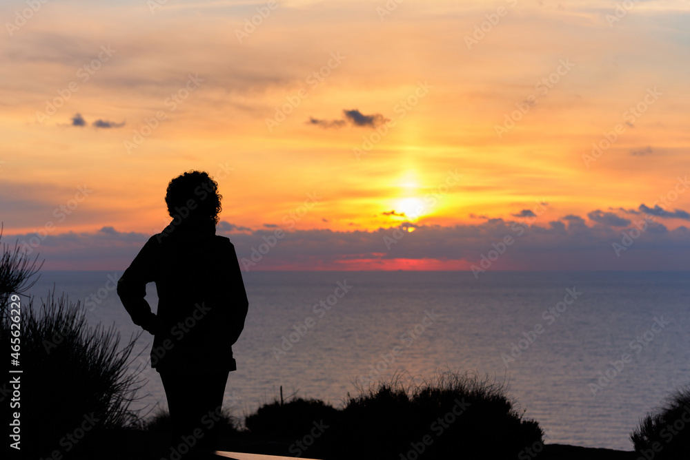 Woman watching the sunrise at sea from a mountain