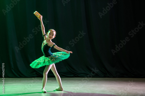Fototapeta Naklejka Na Ścianę i Meble -  A little girl ballerina is dancing on stage in a tutu on pointe shoes with a tambourine, a classic variation of Esmeralda.