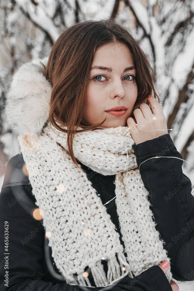 Woman is smiling and holding fairy lights in winter park. Woman is smiling and holding fairy lights in winter park.