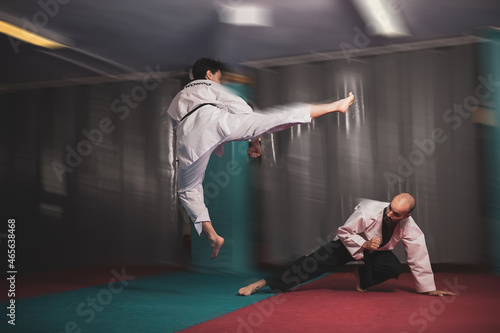 two masters of taekwondo fighting in a match.