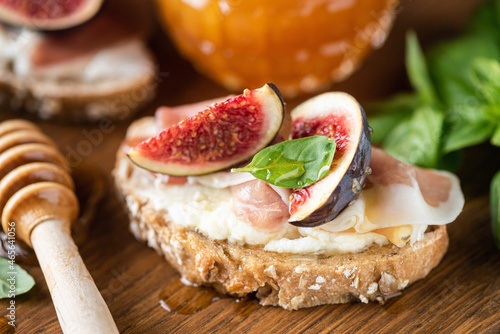 Bruschetta with figs, prosciutto and ricotta cheese, closeup view. Tasty gourmet toast