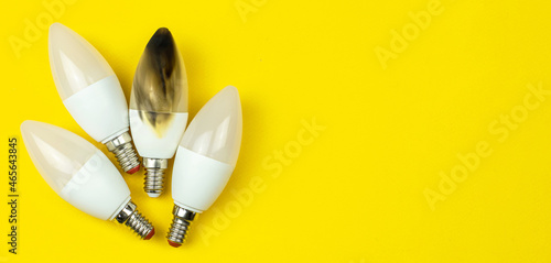 Broken and burn out LED light bulb after fire. Home safety concept. Top view, copy space, yellow background