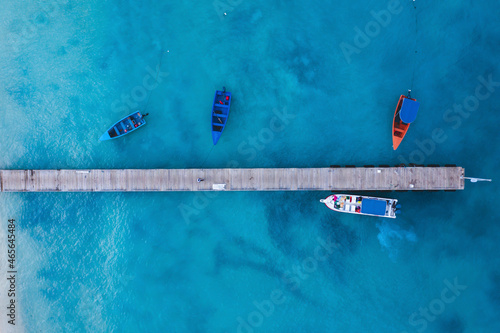 Colorful boats at the pier against the background of turquoise water. Background from top view. Drone shot. Exotic travel tourism concept