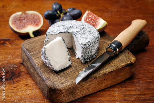 Traditional French Chevre goat milk cheese with fig and grapes offered as close-up on a wooden board photo