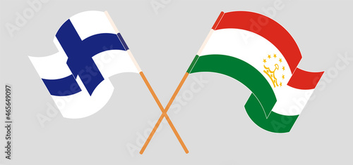 Crossed and waving flags of Finland and Tajikistan