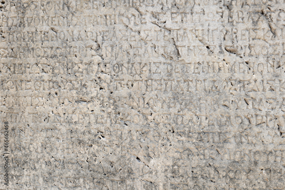 Ancient Greek inscriptions on stone in archeological ruin in ancient Greece site - design, background, texture, creative use