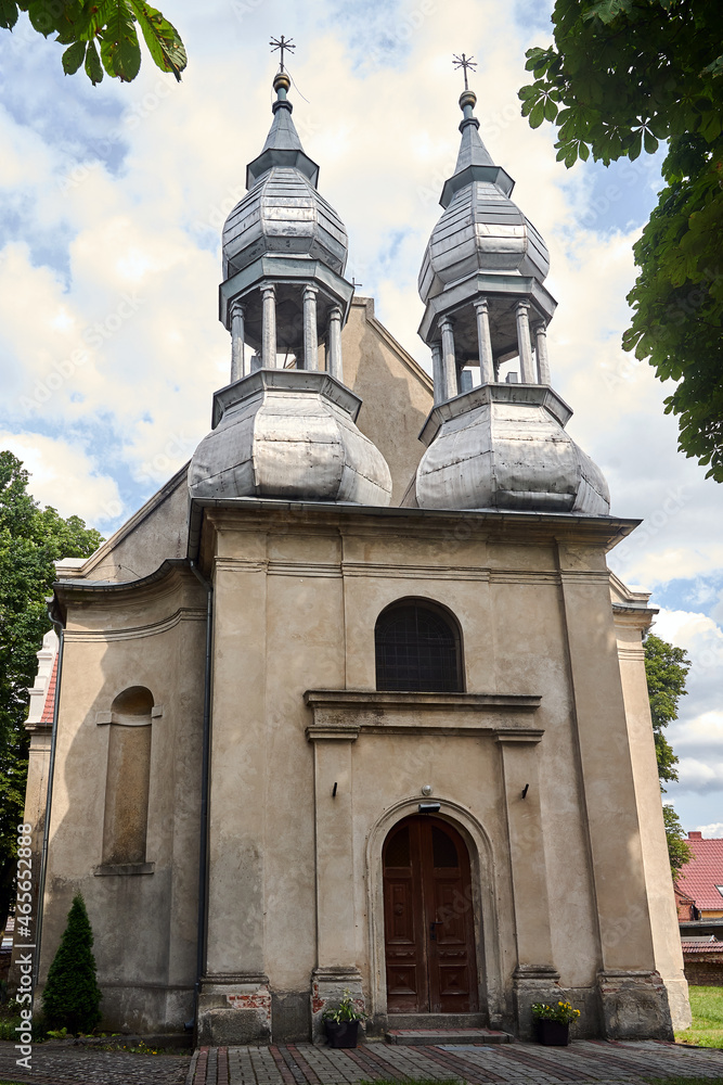 The facade of the historic baroque church with tin belfries in Stary Dworek