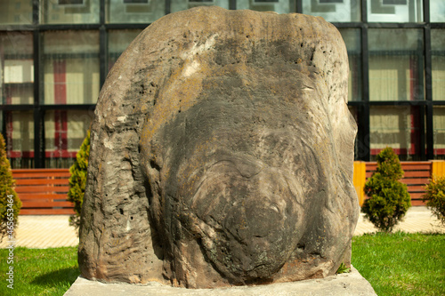 A large stone in the park. A block adorns the street.