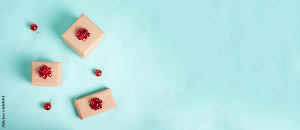 Banner of gift boxes wrapped in kraft paper and tied with red christmas bow on a blue background