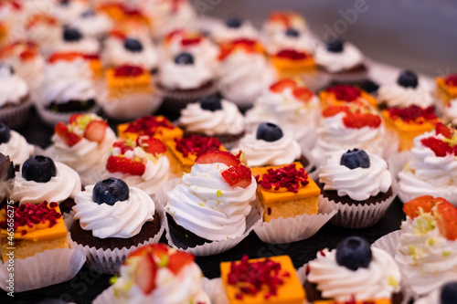 Mini cake selection. Orange cheese cake. Pavlova with strawberry. Chocolate muffin with mascarpone. Delicious professional looking food and snacks served at catering event or party buffet style.