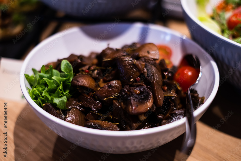 Bowl of smoked and marinated mushrooms. Delicious professional looking food and snacks served at catering event or party buffet style.