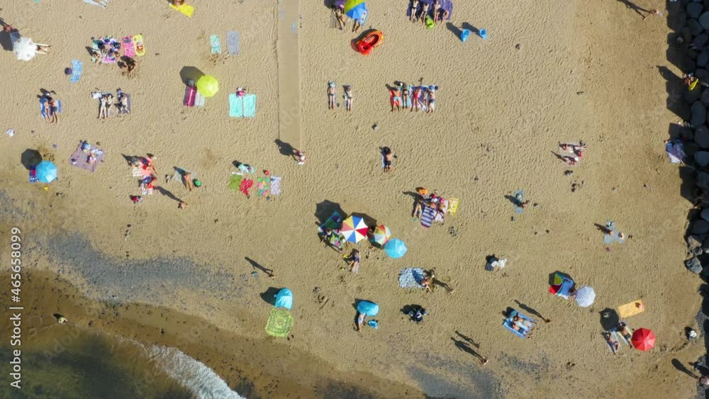 Aerial top down view of the beach with people resting on sun loungers and with beach umbrellas Aerial top down view of the beach with people resting on sun loungers and with beach umbrellas