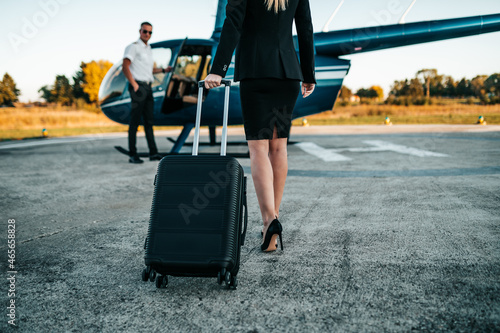 Attractive middle age business woman standing on airport and using private air transport chopper or helicopter to travel to a business meeting.