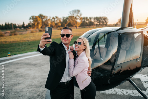 Wealthy young business couple is preparing to use their own private chopper or helicopter to travel on vocation or business meeting. photo