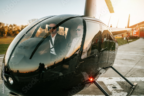 Wealthy young business couple is preparing to use their own private chopper or helicopter to travel on vocation or business meeting.