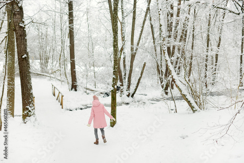 Adorable girl having fun in beautiful winter park during snowfall. Cute child playing in a snow. Winter activities for family with kids. © MNStudio