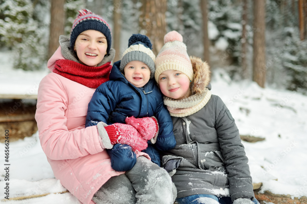 Two big sisters and their baby brother having fun outdoors. Two young girls holding their baby boy sibling on winter day. Kids with large age gap. Two big sisters and their baby brother having fun outdoors. Two young girls holding their baby boy sibling on winter day. Kids with large age gap.
