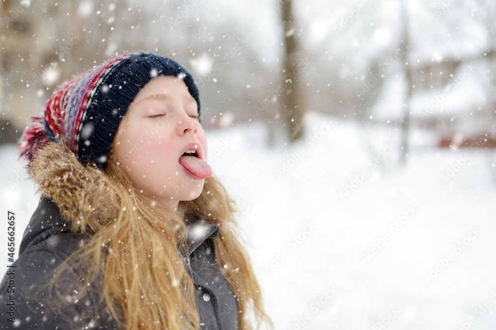 Adorable girl having fun in beautiful winter park during snowfall. Cute child playing in a snow. Winter activities for family with kids. Adorable girl having fun in beautiful winter park during snowfall. Cute child playing in a snow. Winter activities for family with kids.